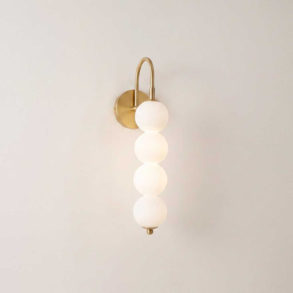 Stacked globe wall lamp with four opal globes on a curved copper-tone arc, studio shot on warm off-white background