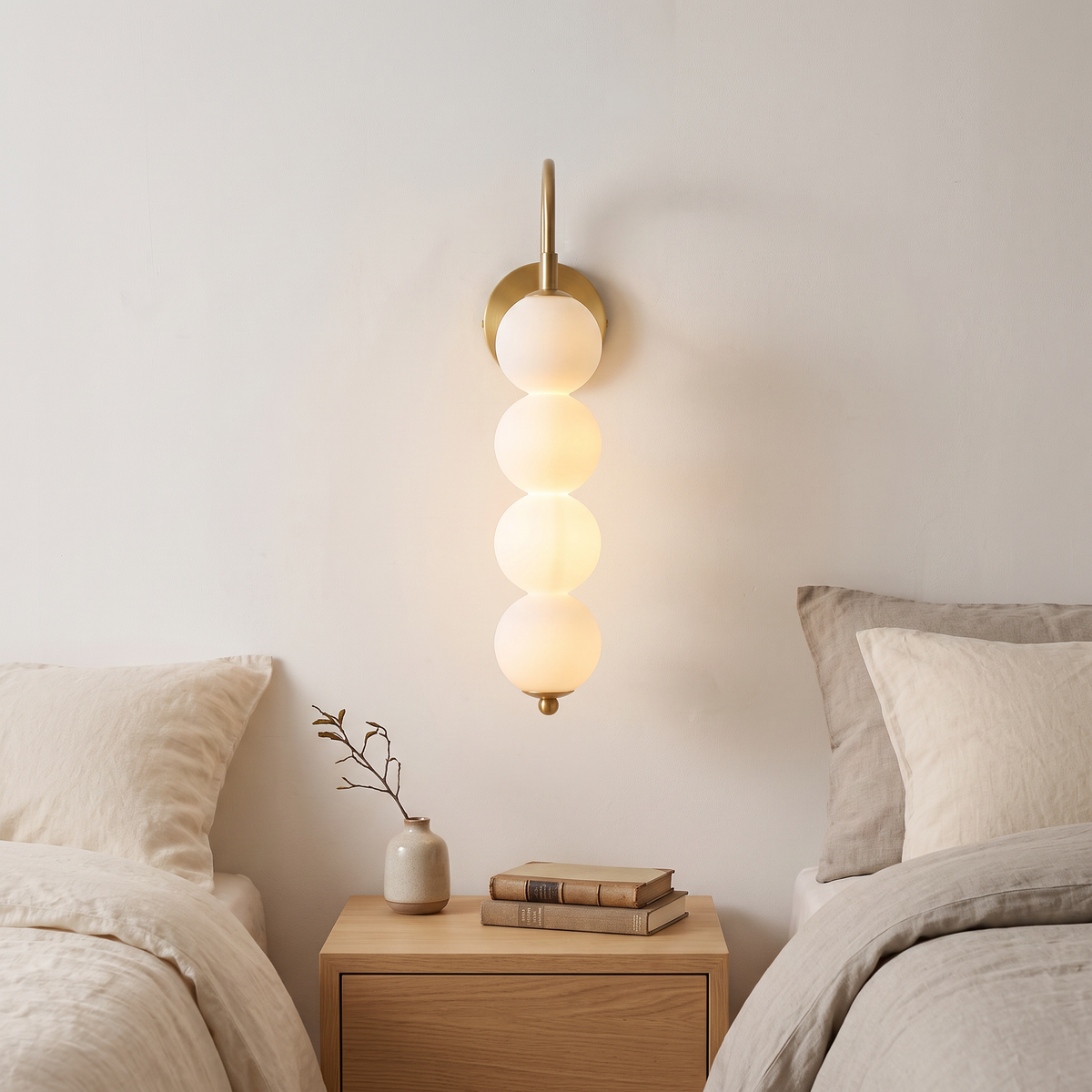 Stacked globe wall lamp with four opal globes lit beside a bed in a calm Nordic bedroom